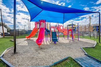 A playground with a blue canopy and a red slide.
